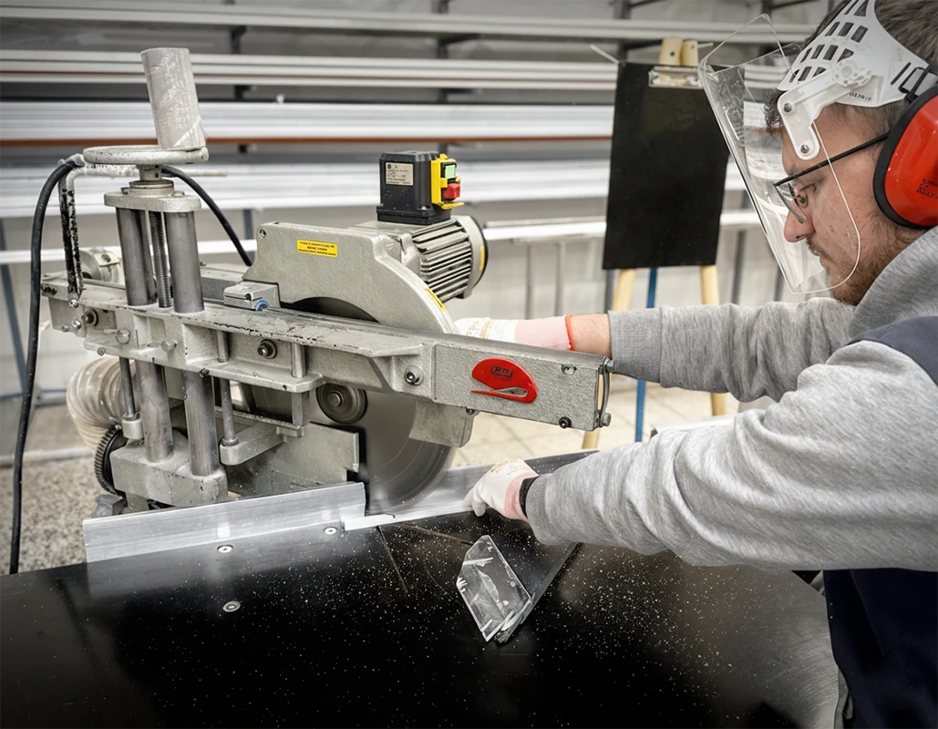 ýroba plisovanej siete proti hmyzu – rezanie hliníkového rámu na mieru v dielni.